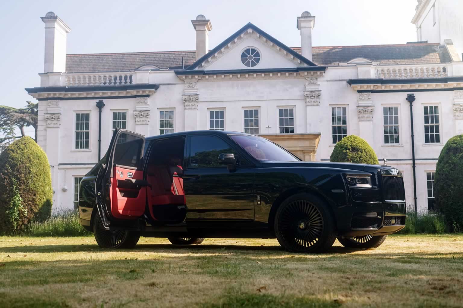 Black Badge Rolls-Royce Cullinan 3/4 front with coach doors open showing red leather interior upolstery
