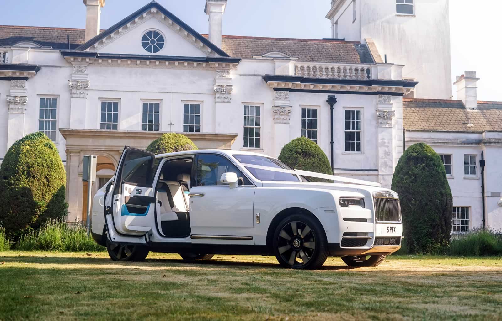 White Rolls-Royce Cullinan wit wedding ribbons and rear coach doors open