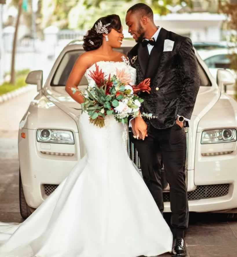 Couple in front of a white Rolls-Royce Ghost weddiing car - bride is wearing a trumpet/mermaid style wedding dress.