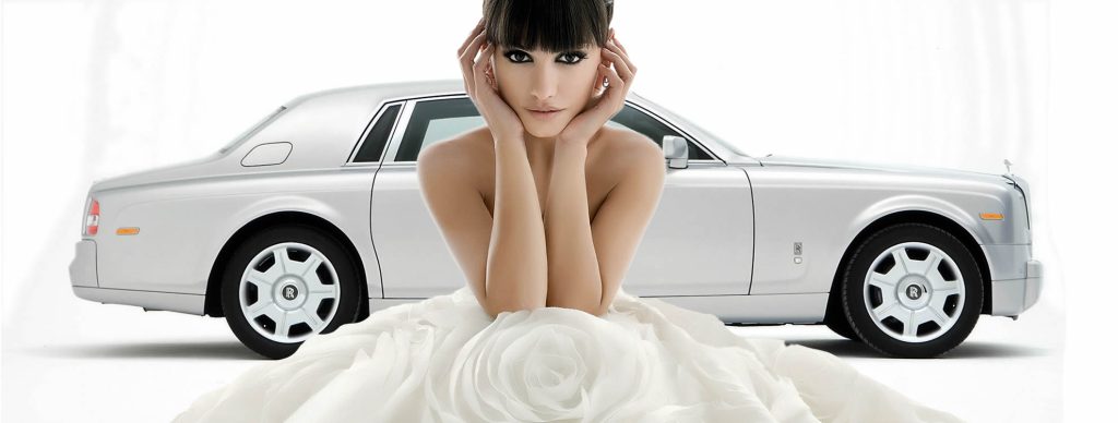 Bride in a white wedding dress in front of a white Rolls-Royce Phantom wedding car