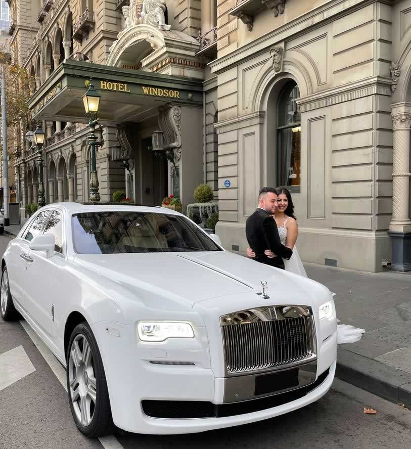 White Rolls-Royce Phantom 8 Eight wedding car with briide and groom standing beside it - the bride is wearing an empire line bridal gown.