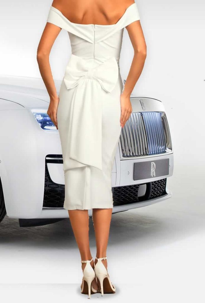 Bride wearing tea length wedding dress with a big bow behind paired with a white Rolls-Royce Ghost wedding car.